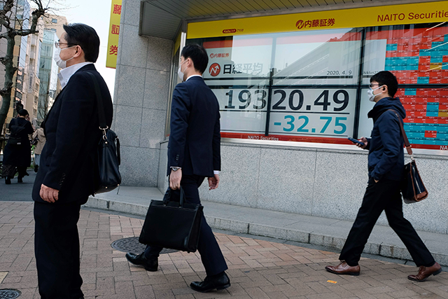 Pedestrians walk past a quotation board displaying share prices of the Tokyo Stock Exchange in Tokyo on April 9, Thursday (AFP photo)