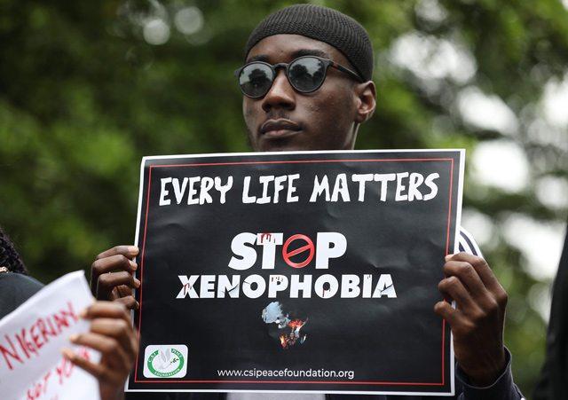 A demonstrator holds a sign during a protest against xenophobia outside of the main gate of the South African high commission which was shut down to avert reprisal attacks in Abuja on Thursday (AFP photo)