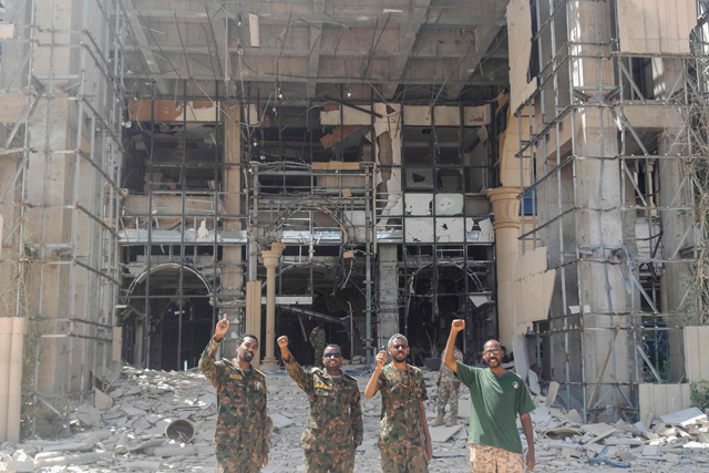 Soldiers of the Sudanese army or affiliated forces pose for a picture while pumping their fists at the damaged presidential palace after recapturing the complex from RSF paramilitaries in Khartoum on March 21, 2025 (AFP photo)  