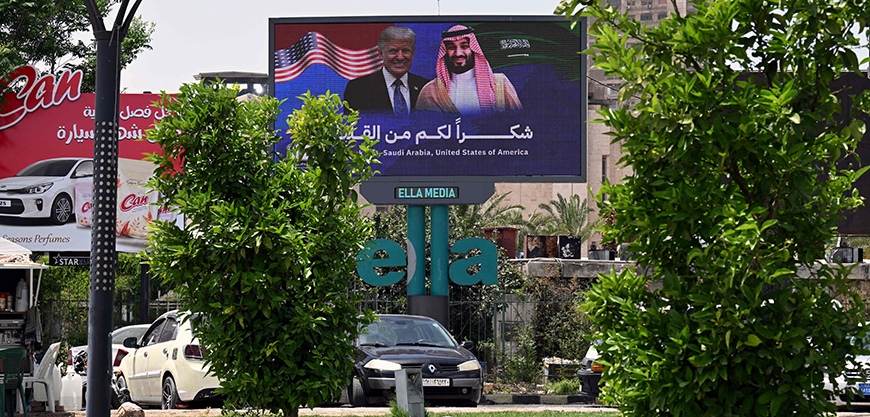 A Muslim man prays in Damascus near a billboard displaying Syria's interim president Ahmed al-Sharaa and US President Donald Trump with a slogan thanking Saudi Arabia and the United States, on Wednesday (AFP photo)