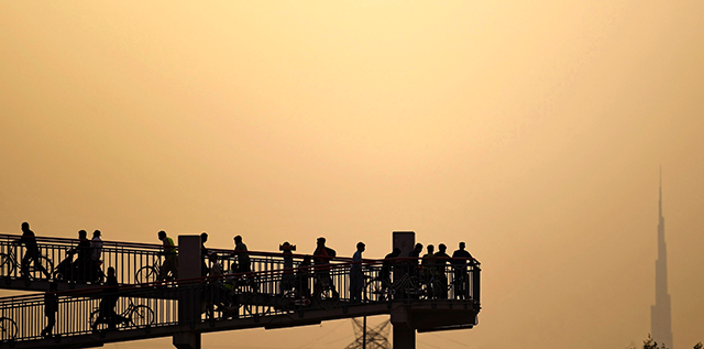People walk or ride bicycles over a bridge, during the novel coronavirus pandemic crisis, in the Emirati city of Dubai, on April 2, 2020. (AFP photo)