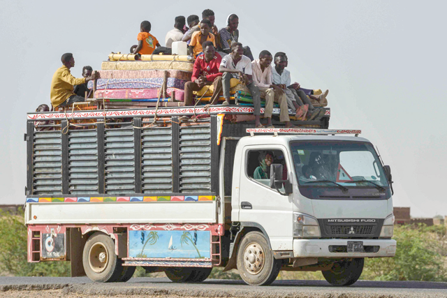 People ride with furniture and other items atop a truck moving along a road from Khartoum to Wad Madani at the locality of Kamlin, about 80 kilometres southeast of Khartoum, on June 22 (AFP photo)