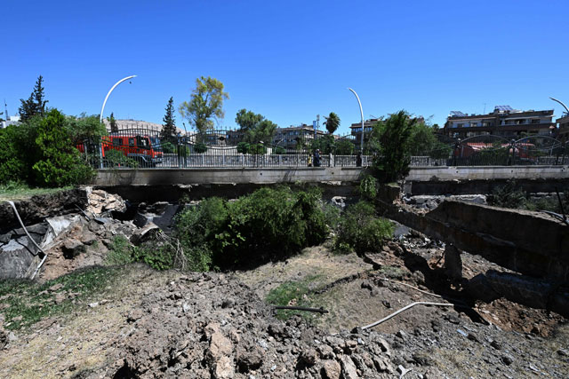 A fire truck is parked on a bridge near a crater caused by an Israeli strike in the neighbourhood of Kafr Sousse in Damascus, early on Sunday (AFP photo)