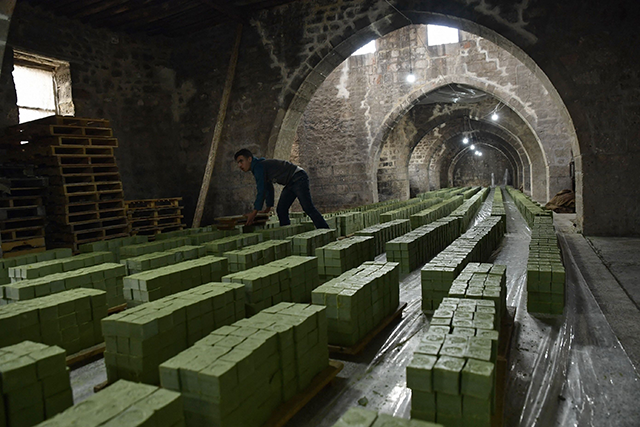A Syrian worker stacks laurel soap at the Jbaili soap factory, an 800 year old artisanal soap manufacturer, in the old city of Syria's northern city of Aleppo on January 24, 2022 (AFP photo)
