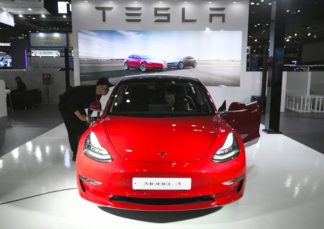 In this file photo taken on March 27,  visitors look at a Tesla Model 3 during a press preview of the Seoul Motor Show in Goyang, northwest of Seoul  (AFP photo)