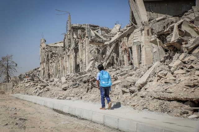 In this undated photo, a child can be seen walking past damaged buildings in Iraq (Photo courtesy of UNICEF’s website)