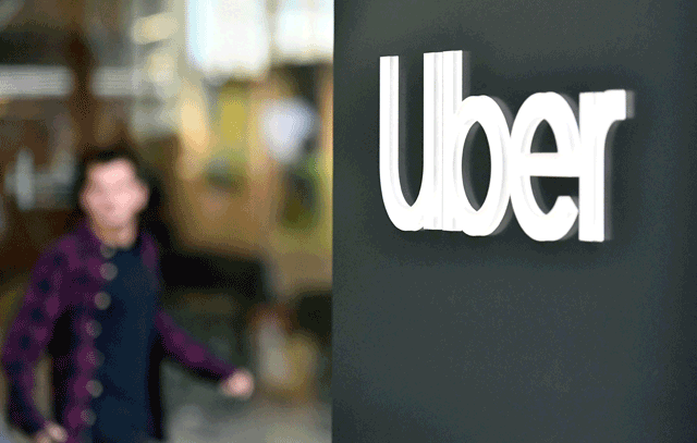 This file photo taken on May 8, 2019, shows an Uber logo on a sign outside the company's headquarters location as people protest nearby in San Francisco, California  (AFP photo)