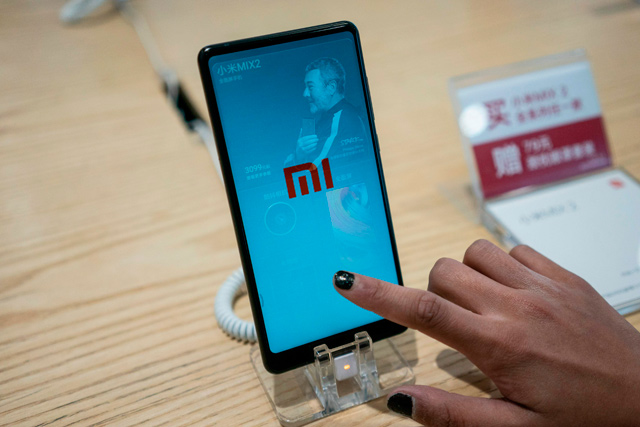 This photo taken on May 3 shows a customer looking at a Xiaomi smartphone in a shop in Beijing (AFP file photo)