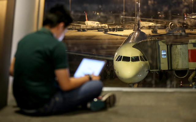 A man checks his tablet computer at the departures lounge as an airliner is seen parked at the apron in the background at Ataturk International Airport in Istanbul, Turkey, on Wednesday (Anadolu Agency photo )