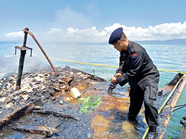 This handout photo taken on Saturday and released by Kendari Police shows an Indonesian policeman inspecting the charred remains of a ferry that caught fire near Kendari, off Indonesia's Sulawesi island (AFP photo)