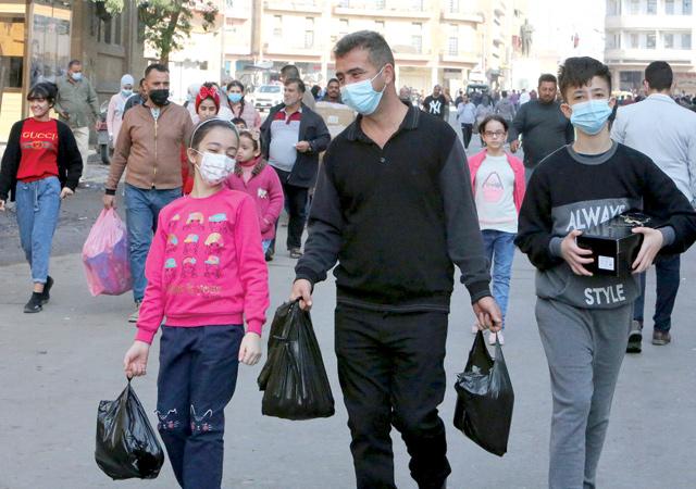 Iraqis wearing face masks amid the COVID-19 pandemic, walk with their shopping in the capital Baghdad, on December 4,  While much of the world fears COVID-19, Iraqis have mostly stopped wearing face masks as they worry more about the pandemic's economic impact than the virus itself (AFP photo)