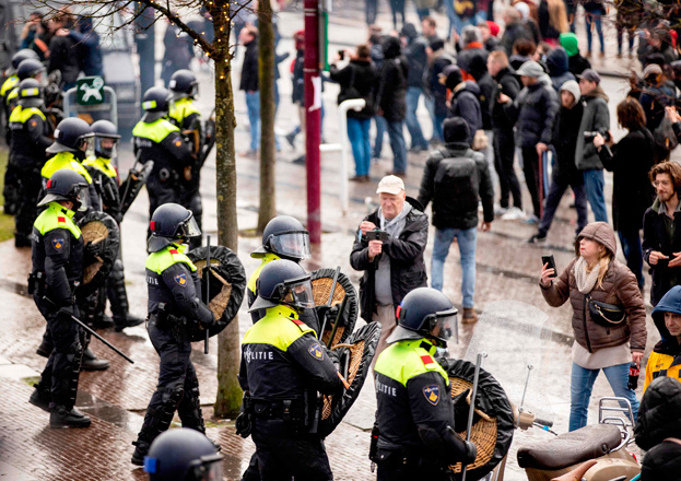 Dutch riot police stand near anti-government activists as they denounce ongoing restrictions related to the coronavirus disease (COVID-19) pandemic among other issues in Museumplein, Amsterdam, on Sunday (AFP photo)