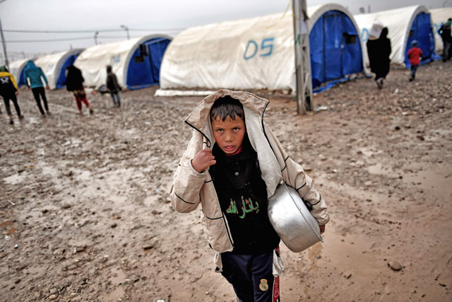 A displaced Iraqi boy from Mosul walks under the rain at the Hamam Al Alil camp on Monday, during the government forces ongoing offensive to retake the western parts of the city from Daesh extremists (AFP photo)