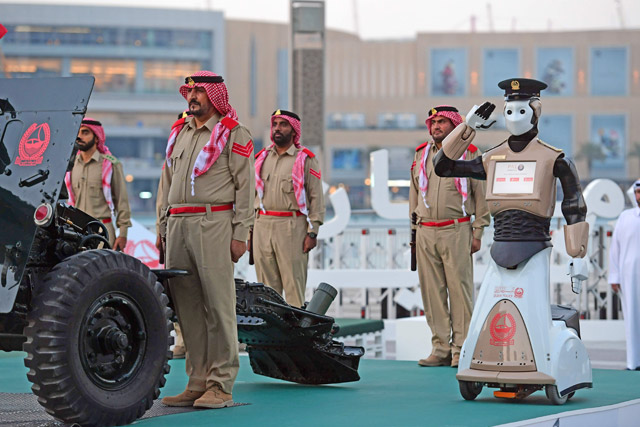 The world's first operational police robot stands to attention near the Burj Khalifa in downtown Dubai on Wednesday, as a military cannon is prepared to be fired at sunset marking the end of the fasting day for Muslims observing Ramadan (AFP photo)