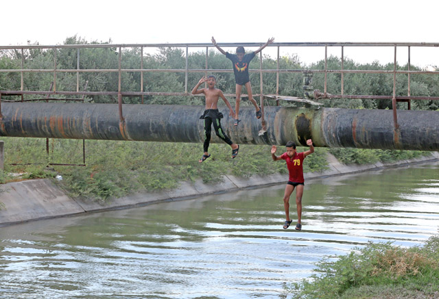 Children play in water in Northern Shouneh on Saturday (Photo by Raed Adayleh)