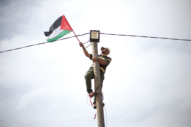 A man hangs a Palestinian flag at an electric pole near the border with Israel, in the southern Gaza Strip, on Wednesday (Reuters photo)