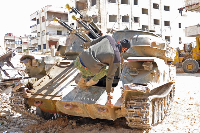 A Syrian government soldier jumps into an anti-aircraft armoured vehicle in Al Hajar Al Aswad, on Sunday, during a regime offensive targeting Daesh terror group in the southern districts of Damascus (AFP)