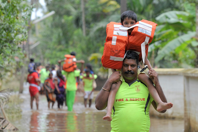 Kerala and Tamil Nadu Fire Force personnel carry children on their shoulders through floodwaters during a rescue operation in Annamanada village in Thrissur District in the south Indian state of Kerala on Sunday (AFP photo)
