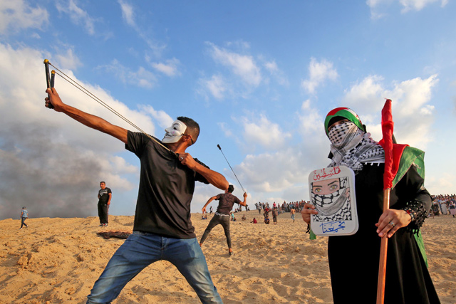 Palestinian protesters use slingshots at a demonstration on the beach near the maritime border with Israel, in the northern Gaza Strip, on Monday (AFP photo)