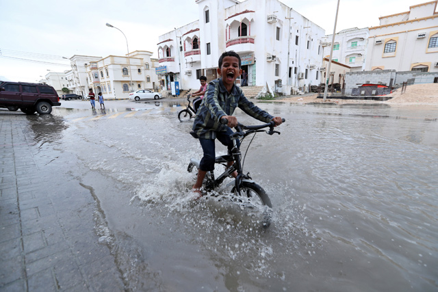 A child plays in a roadside puddle accumulated from rain brought by Cyclone Luban in Salalah, Oman, on Saturday (Reuters photo)
