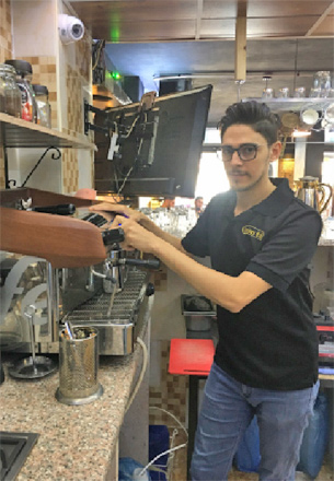 Saif Al Sharaa serving coffee at his thriving ‘Luminus’ café  (Photo courtesy of Saif Al Sharaa)