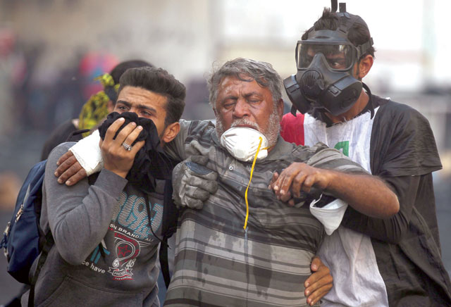 Iraqi volunteers help a protester affected by tear gas fired by security forces amid clashes at Baghdad's Khallani Square during ongoing anti-government demonstrations on Friday (AFP photo)