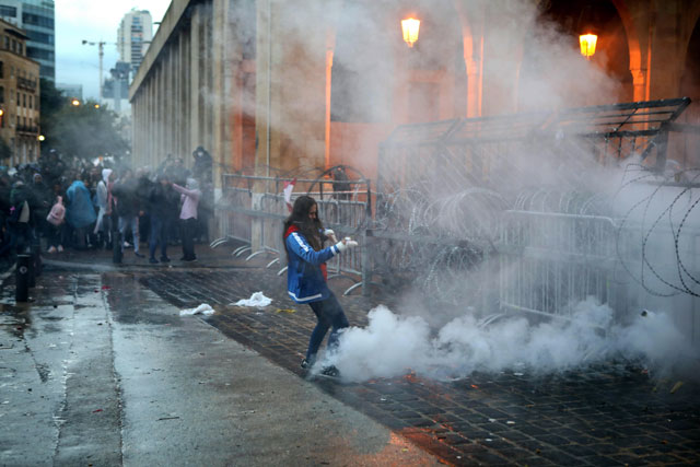 A Lebanese anti-government protester kicks back a tear gas canister fired by riot police from behind the barricaded road leading to parliament in central Beirut on Sunday (AFP photo)
