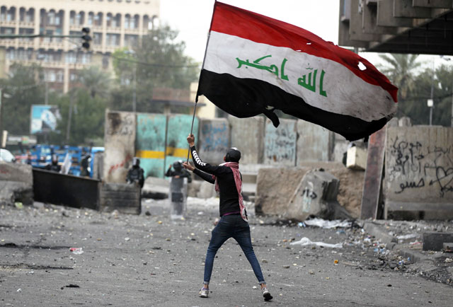 An Iraqi protester waves the national flag amid clashes with riot police at Baghdad’s Al Khilani Square on February 19, during ongoing anti-government demonstrations (AFP photo)