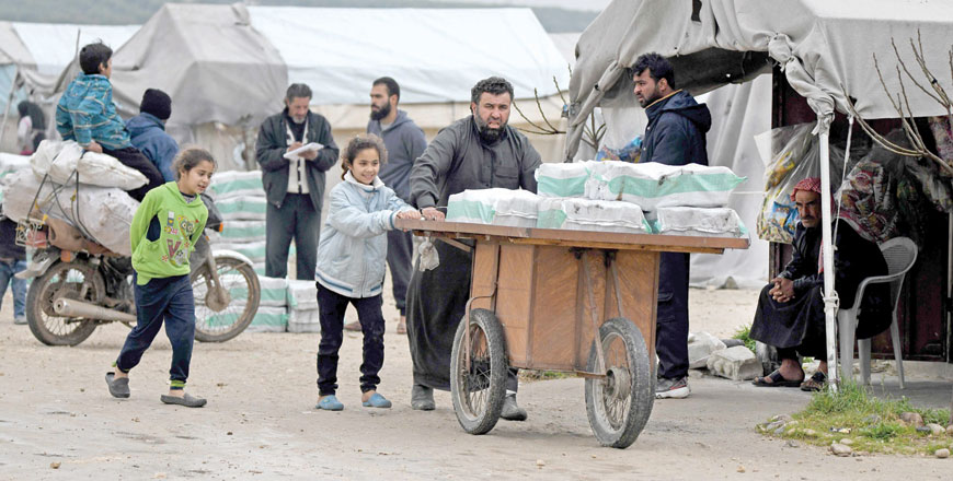 Displaced Syrians receive aid, consisting of heating material and drinking water, at a camp in the town of Mehmediye, near the town of Deir Al Ballut along the border with Turkey, on Friday (AFP photo)