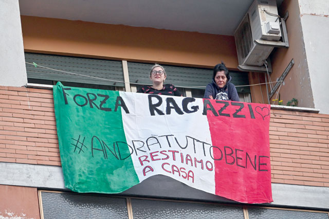 People sing, wave and clap their hands next to a banner reading 'Forza ragazzi hastag #andratuttobene, restiamo a casa' (Come on, guys #everythingsgonnabeallright, we stay home), during a flash mob 'Una canzone per l'Italia' (A song for Italy) at the Magliana district in Rome on Saturday (AFP photo)