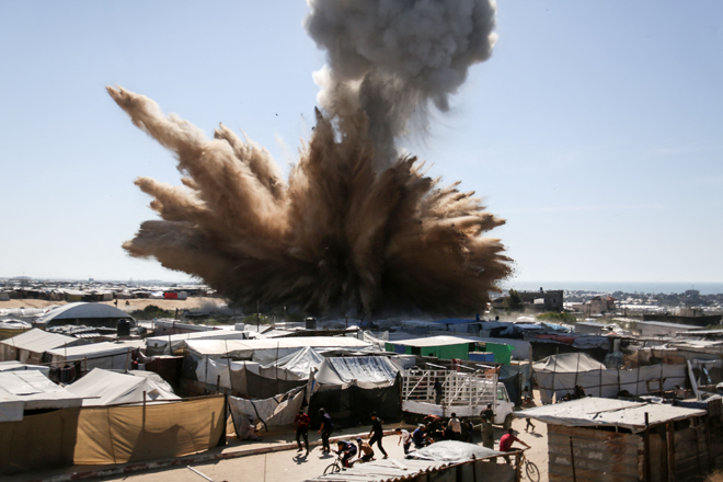 People run for cover as a plume of smoke rises above tents at a camp for displaced Palestinians in northern Khan Yunis in the southern Gaza Strip, during an Israeli strike on April 19, 2025 (AFP photo)