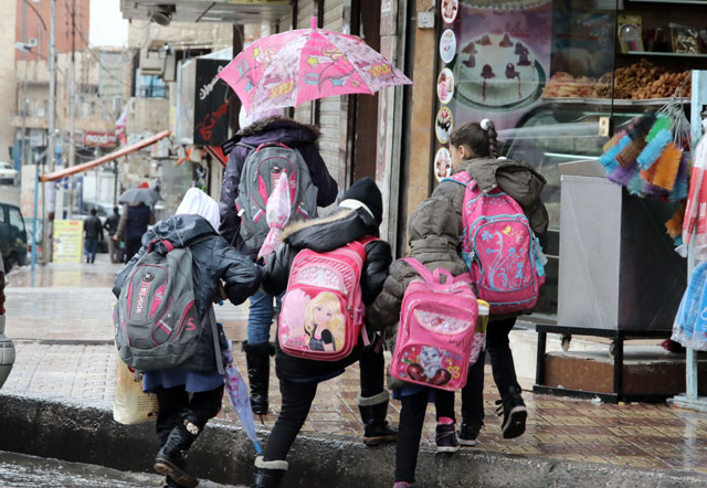 Schoolgirls walk in the rain in Amman last week (Photo by Osama Aqarbeh)