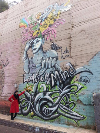 Palestinian graffiti artist Laila Ajjawi stands recently next to one of her murals in Ras Al Ain, Amman (Photo courtesy of Laila Ajjawi)