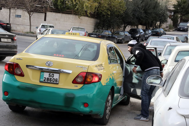 A pedestrian speaks to a taxi driver on a street in Amman on Thursday (Photo by Osama Aqarbeh)