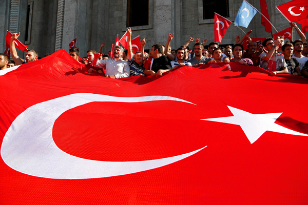 Turkish citizens wave a huge national flag as they protest against the military coup outside Turkey’s parliament near the Turkish military headquarters in Ankara, Turkey, on Saturday (AP photo)
