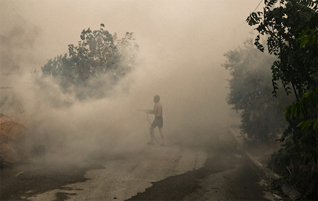 A local resident attempts to extinguish a fire in Nea Anchialos, near Greek mainland city of Volos, on Thursday (AFP photo)