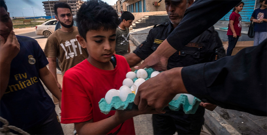 A young flood survivor receives a donation of eggs from the owner of a supermarket in Libya's eastern city of Derna on Tuesday (AFP photo)