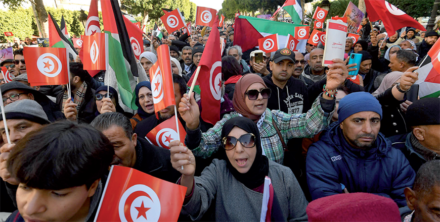 Tunisians wave national and Palestinian flags during a protest marking the 14th year of the 2011 revolution and calling for the release of President's opponents on Habib Bourguiba Avenue in Tunis on Sunday (AFP photo)