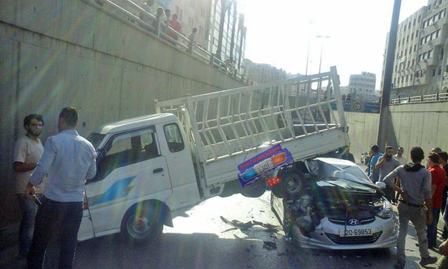 People gather around two vehicles that collided near the Jubilee Tunnel in the Gardens Street in Amman on Tuesday. No injuries were reported in the accident  (Photo courtesy of Amen FM)