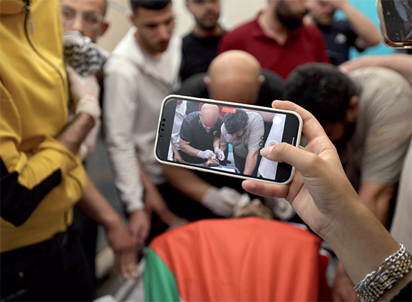 A woman snaps a picture of one of three Palestinians killed during an overnight Israeli raid on Tulkarem in the occupied West Bank, at a hospital morgue on Thursday (AFP photo)