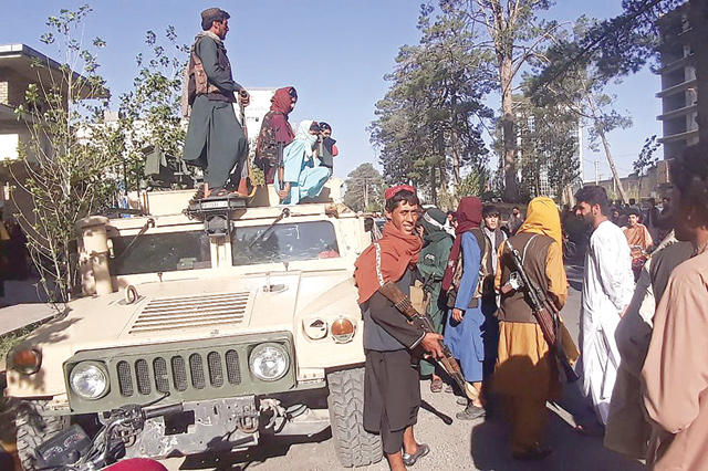 In this photo taken on Friday, Taliban fighters stand guard along the roadside in Herat, Afghanistan's third biggest city, after government forces pulled out the day before following weeks of being under siege. (AFP photo)