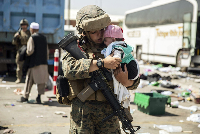 This US Marine photo released on Monday shows a US Marine with the 24th Marine Expeditionary Unit carrying a baby as the family processes through the Evacuation Control Centre during an evacuation at Hamid Karzai International Airport, Kabul, Afghanistan, on Saturday (AFP photo)