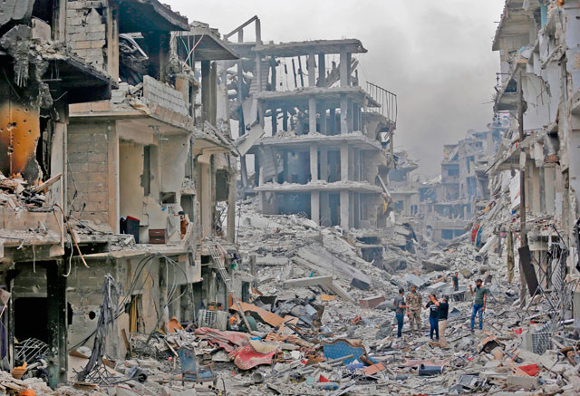 Members of the Syrian pro-government forces inspect the damage of a street in Al Hajar Al Aswad neighbourhood on the southern outskirts of the capital Damascus on Tuesday (AFP)