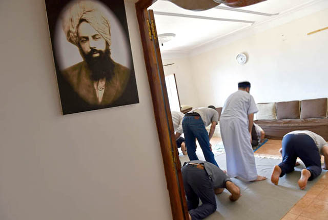 Members of Algeria's small Ahmadi community pray at a house in Tilpasi, west of Algiers, near a photo of Mirza Ghulam Ahmad (1835-1908) the founder of the Ahmadiyya movement, a reformist Islamic movement which is accused of heresy by extremists and targeted by the authorities, on June 30 (AFP photo)