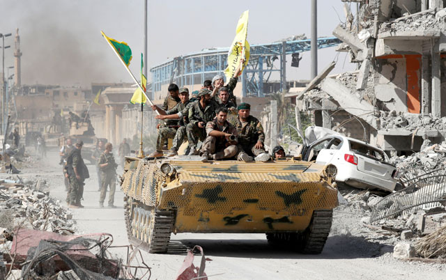 Syrian Democratic Forces fighters ride atop of military vehicle as they celebrate victory in Raqqa, Syria, on Tuesday (Reuters photo)