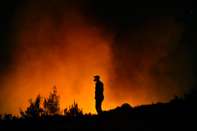 A firefighter tries to extinguish a fire burning near the village of Kapandriti, north of Athens, Greece, on Monday (AFP photo)