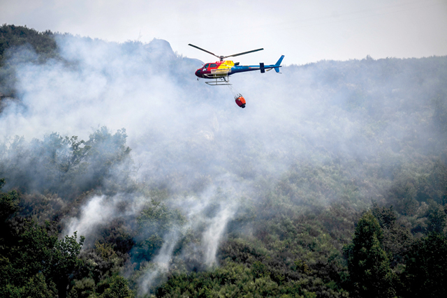 A firefighter helicopter flies over a wildfire near Bustelo village in Amarante, north of Portugal, on Saturday (AFP photo)