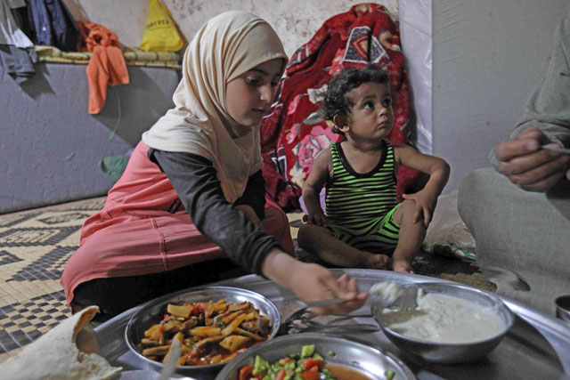 Umm Samer's family, displaced from Eastern Ghouta, gather to break their fast at their home in Maaret Masrin some seven kilometres north of Idlib, on May 26 (AFP photo)