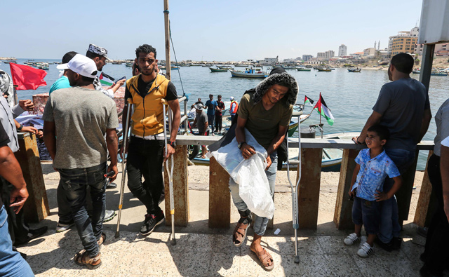 An injured Palestinian (centre) waits on the pier before boarding a blockade-running boat, carrying him with other wounded and students, out from the Gaza City harbour yesterday, to break Israel’s naval blockade on the enclave (AFP photo)