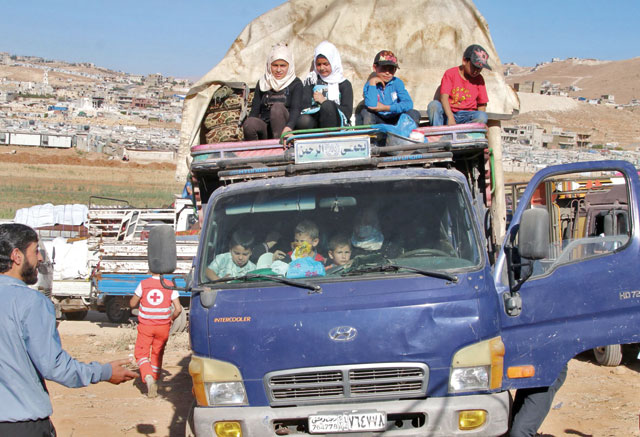 Syrian refugees ride a truck carrying their personal belongings at a Lebanese army checkpoint in Wadi Hmeid in the Bekaa Valley, after leaving the village of Arsal to return to their homes in Syria's Qalamoun region on Tuesday (AFP photo)